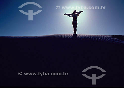  Women with arms wide open over a dune 