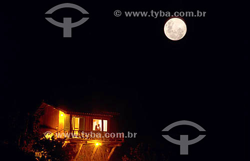  Couple inside a house with full moon above it 