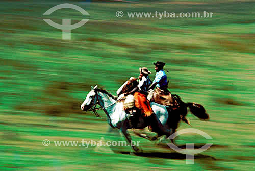  Two men riding their horses on a prairie 