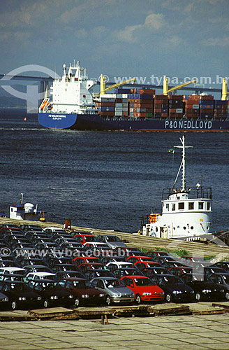  Rio de Janeiro city Port full of cars for exportation with a cargo ship full of containers and Rio-Niteroi bridge in the background - Rio de Janeiro state - Brazil 