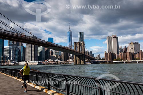  Woman exercising on the banks of the East River with the Brooklyn Bridge in the background  - New York city - New York - United States of America