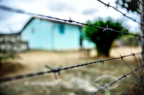  Detail of fence of barbed wire with house in the background  - Jacobina city - Bahia state (BA) - Brazil