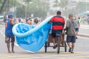 Men carrying an inflatable pool on the shore of Copacabana Beach. - Rio de Janeiro city - Rio de Janeiro state (RJ) - Brazil