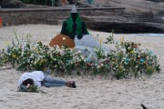 Offerings for Yemanja and a person sleeping on the sand during the party on the day of the Queen of the Sea - Arpoador Beach - Rio de Janeiro city - Rio de Janeiro state (RJ) - Brazil